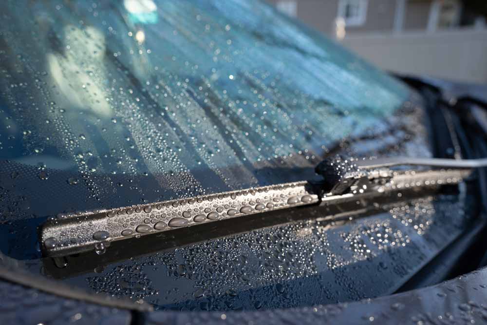 Close up of a car windshield with raindrops and wipers